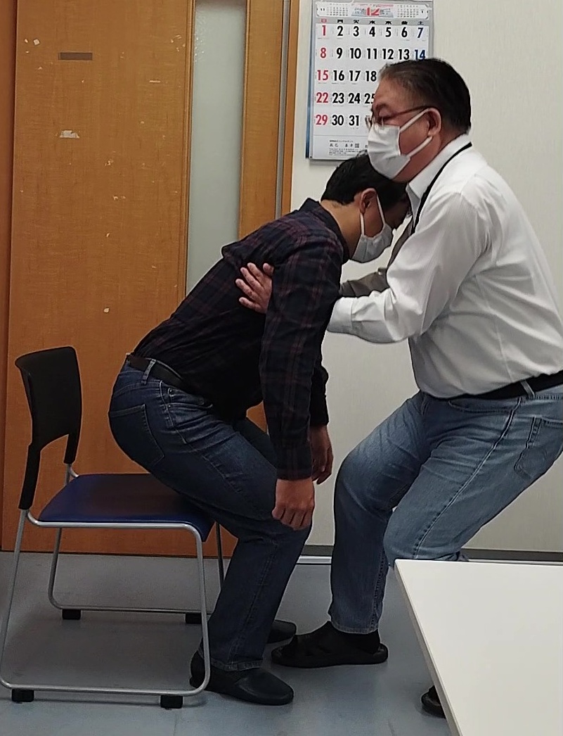 介助する人が、椅子から立ち上がろうとする人を支えている様子